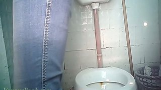 Mature white lady in blue jeans and jacket pisses in the toilet
