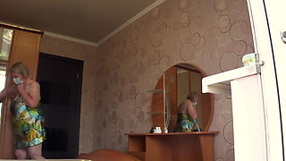 A neighbor watches a mature housewife through an open window.