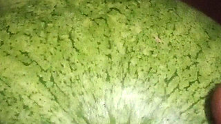 Native Indian lone boy punching his fist with watermelon in the field