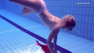 playful blonde girl swims naked in olympic swimming pool