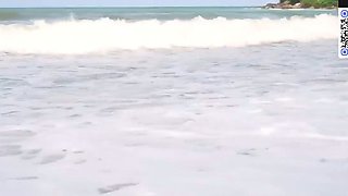 A brown-haired chick in a white bathing suit top gives a